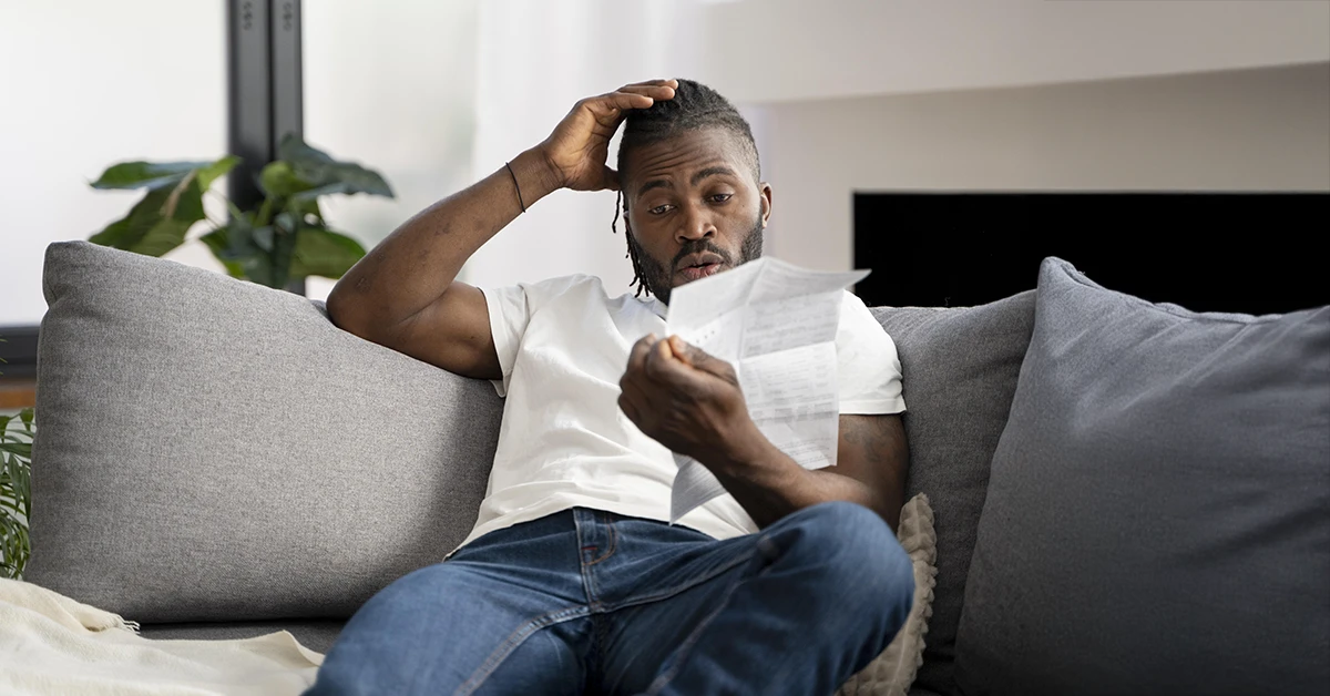 A man is holding an eviction notice in his left hand, looking perplexed about how to pay his bills